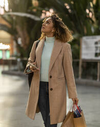 Woman holding mobile phone and shopping bags - JCCMF08538