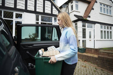 Mädchen mit Mülltonne vor einem Haus am Auto stehend - PMF02418
