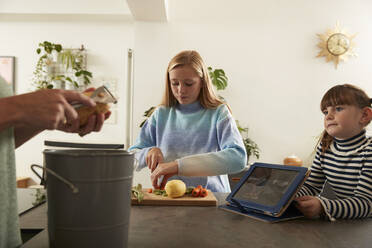 Mädchen mit Schwester und Mutter bei der Zubereitung von Essen in der Küche zu Hause - PMF02427