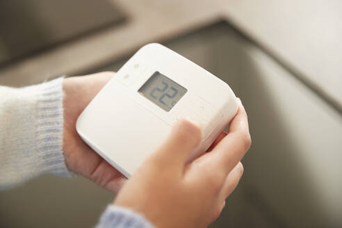Hände eines Mädchens beim Einstellen des Thermostats zu Hause - PMF02440