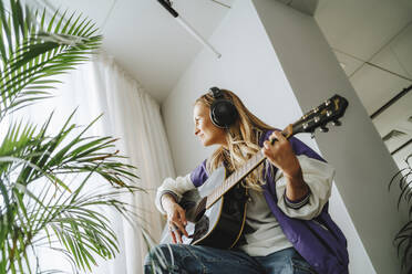 Gitarrist mit Kopfhörern spielt Gitarre im Studio - MDOF00313