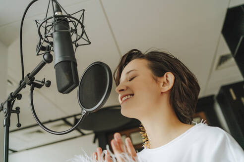 Lächelnde Sängerin, die im Studio Musik über ein Mikrofon aufnimmt - MDOF00336