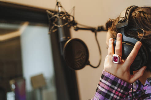Hand des Sängers auf dem Kopfhörer im Studio - MDOF00357