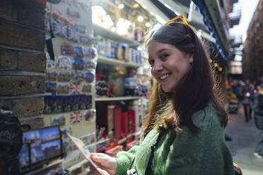 Smiling young woman buying souvenirs at store - ASGF03151