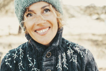 Nachdenkliche reife Frau mit zahnigem Lächeln in warmer Kleidung - SIPF02868