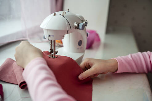 Hände eines Mädchens, das zu Hause an der Nähmaschine Kleidung näht - ANAF00634