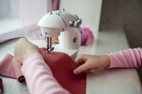 Hands of girl sewing clothes on sewing machine at home - ANAF00634