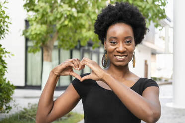 Smiling woman making heart gesture with hands - SVKF00896