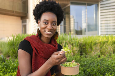 Happy woman having salad outside building - SVKF00907