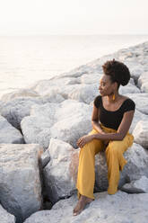 Frau sitzt auf einem Felsen und schaut aufs Meer - SVKF00918