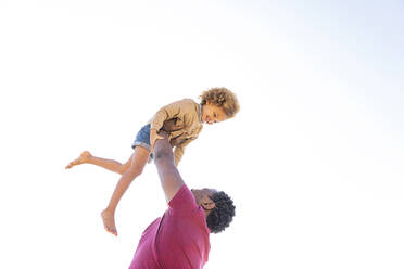 Glücklicher Vater spielt mit Tochter unter klarem Himmel an einem sonnigen Tag - MEGF00292