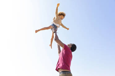 Playful father catching daughter under clear sky on sunny day - MEGF00294