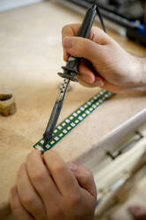Hands of technician soldering circuit board at workshop - ANAF00646