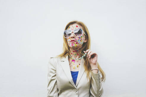 Frau mit bunten Aufklebern im Gesicht vor weißem Hintergrund - SVCF00243