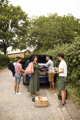 Eine Familie hilft sich gegenseitig beim Einladen von Picknickutensilien in den Kofferraum - MASF33447