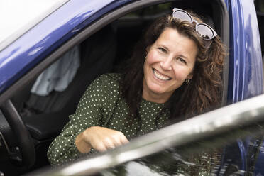 Porträt einer glücklichen Frau mit Sonnenbrille im Auto sitzend - MASF33456