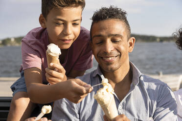 Glücklicher Vater teilt Eis mit seinem Sohn während des Sommerurlaubs - MASF33470