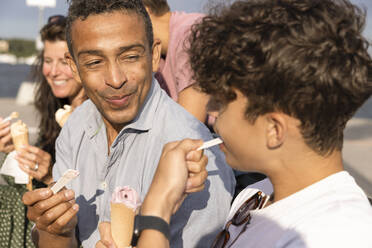 Smiling father looking at son eating ice cream - MASF33471