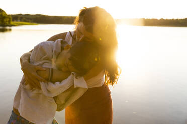 Mother wrapping son with towel after swim during vacation - MASF33494