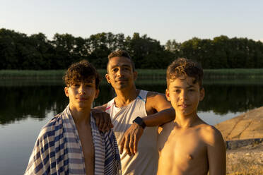 Porträt eines Vaters mit Söhnen im Urlaub bei Sonnenuntergang - MASF33504