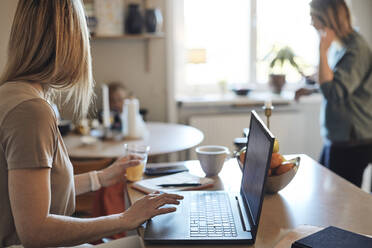 Freiberuflerin schaut weg, während sie zu Hause am Laptop sitzt - MASF33529