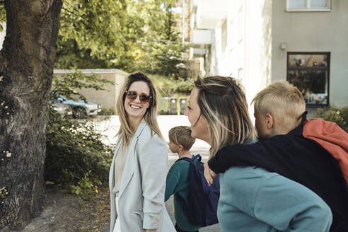 Lesbische Mütter reden miteinander, während sie ihre Söhne zur Schule bringen - MASF33534