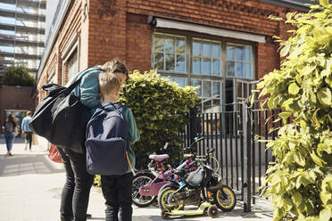 Woman standing with son at school gate on sunny day - MASF33536