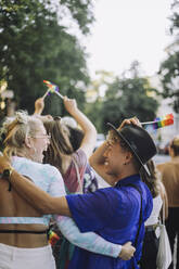 Glücklicher junger Mann, der einen Hut trägt, während er sich mit einer Freundin bei der Gay Pride Parade vergnügt - MASF33574