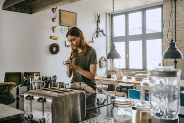 Junge Unternehmerin bereitet Kaffee zu, während sie an der Theke im Studio steht - MASF33635