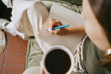 Directly above view of female entrepreneur writing in diary with pen at studio - MASF33641