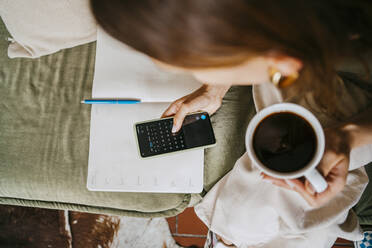 Unternehmer, der einen Kalender auf seinem Smartphone benutzt und eine Kaffeetasse im Studio hält - MASF33644