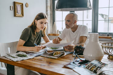 Business colleagues reviewing photograph while working at table in studio - MASF33648