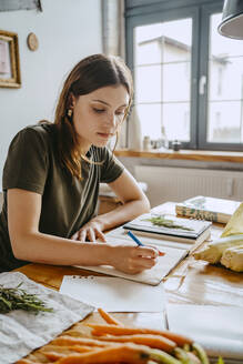 Junge weibliche Food-Stylistin, die im Studio Tagebuch schreibt - MASF33667