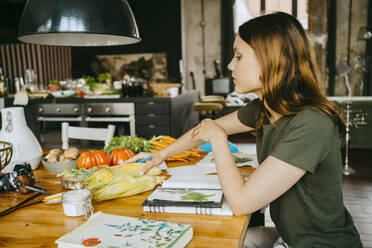 Side view of female food stylist with fresh vegetables on table in studio - MASF33669