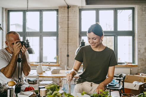 Männlicher Fotograf fotografiert eine Köchin beim Kochen im Studio - MASF33679