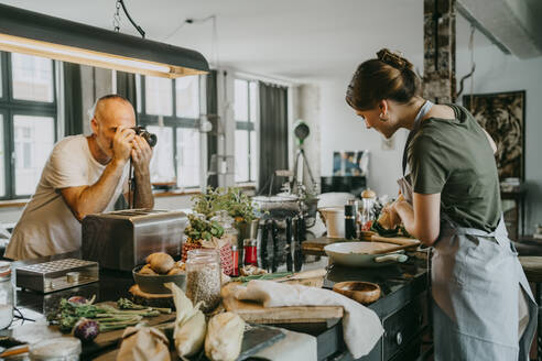 Fotograf, der ein Bild von einem Koch macht, der in einer Studioküche Essen zubereitet - MASF33685