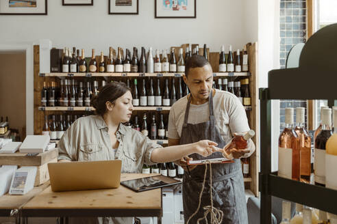 Ein Mann und eine Frau unterhalten sich in einem Geschäft über eine Weinflasche - MASF33774