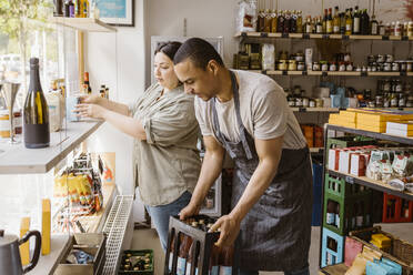 Männliche und weibliche Besitzer helfen sich gegenseitig bei der Arbeit im Weinladen - MASF33780