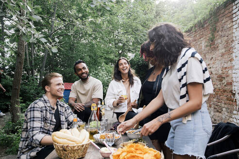 Junge männliche und weibliche Freunde unterhalten sich bei einer Gartenparty im Hinterhof miteinander - MASF33812