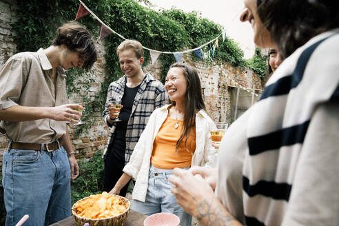 Eine fröhliche Gruppe von Freunden genießt eine Gartenparty mit gutem Essen und viel Gelächter - MASF33816