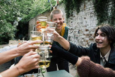 Glückliche Freunde stoßen an und genießen Getränke während einer Dinnerparty im Hinterhof - MASF33860