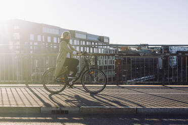 Full length side view of young businesswoman traveling through bicycle on road in city - MASF33890