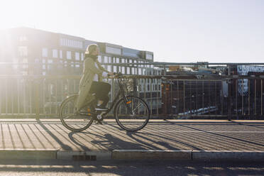 Volle Länge Seitenansicht der jungen Geschäftsfrau Reisen durch Fahrrad auf der Straße in der Stadt - MASF33890