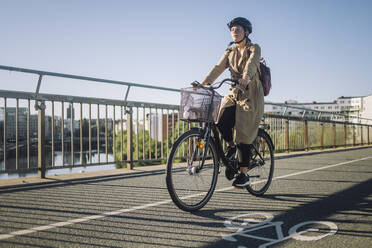 Young businesswoman riding cycle on bicycle lane while commuting to work - MASF33895