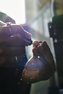 Hände einer Handwerkerin, die in einer Werkstatt einen Ring mit einer Schleifmaschine bearbeitet - DSHF00623