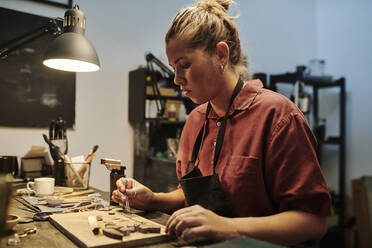 Juwelier bei der Arbeit an einer Werkbank in einer Werkstatt - DSHF00626