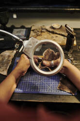 Hands of jeweller polishing golden ring with sand paper on workbench - DSHF00630