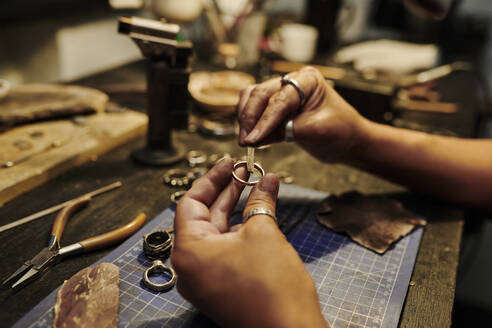 Hands of craftswoman repairing ring at workbench - DSHF00631