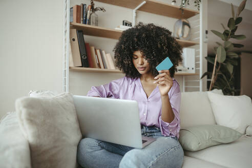 Young woman with credit card doing online shopping on laptop at home - RCPF01595