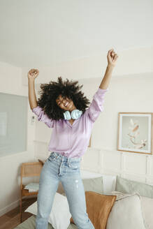 Afro woman enjoying and dancing on bed in bedroom - RCPF01637